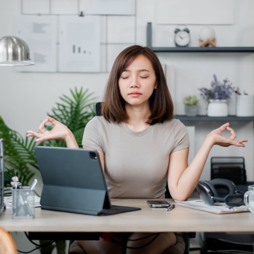 Young woman in zen pose at her laptop
